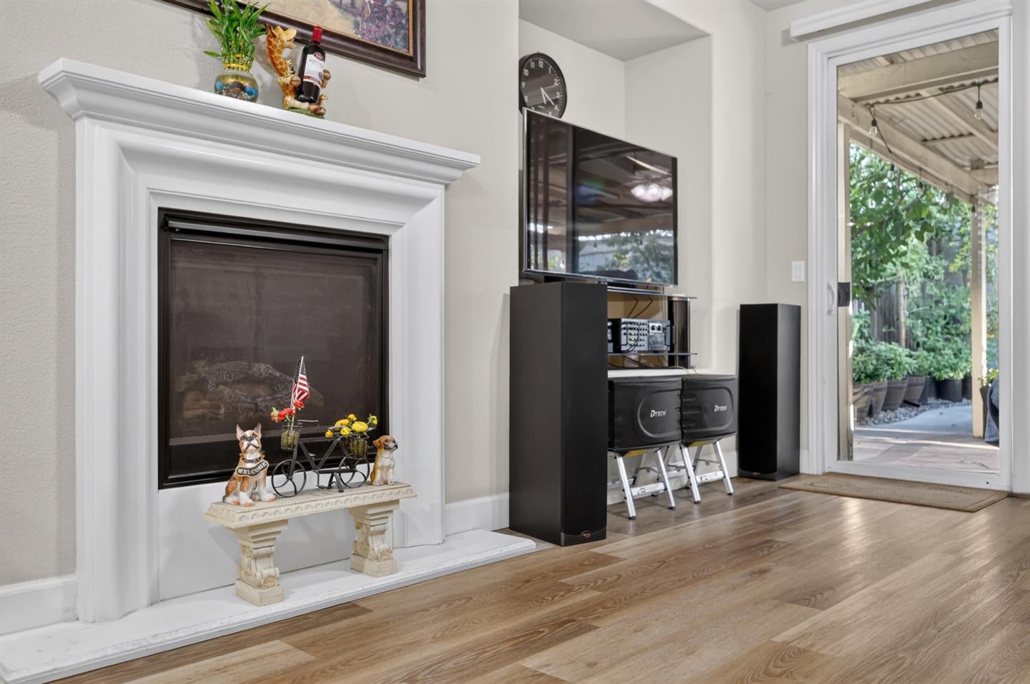 Living room with a white fireplace, wood floors, and glass doors opening to a covered patio.