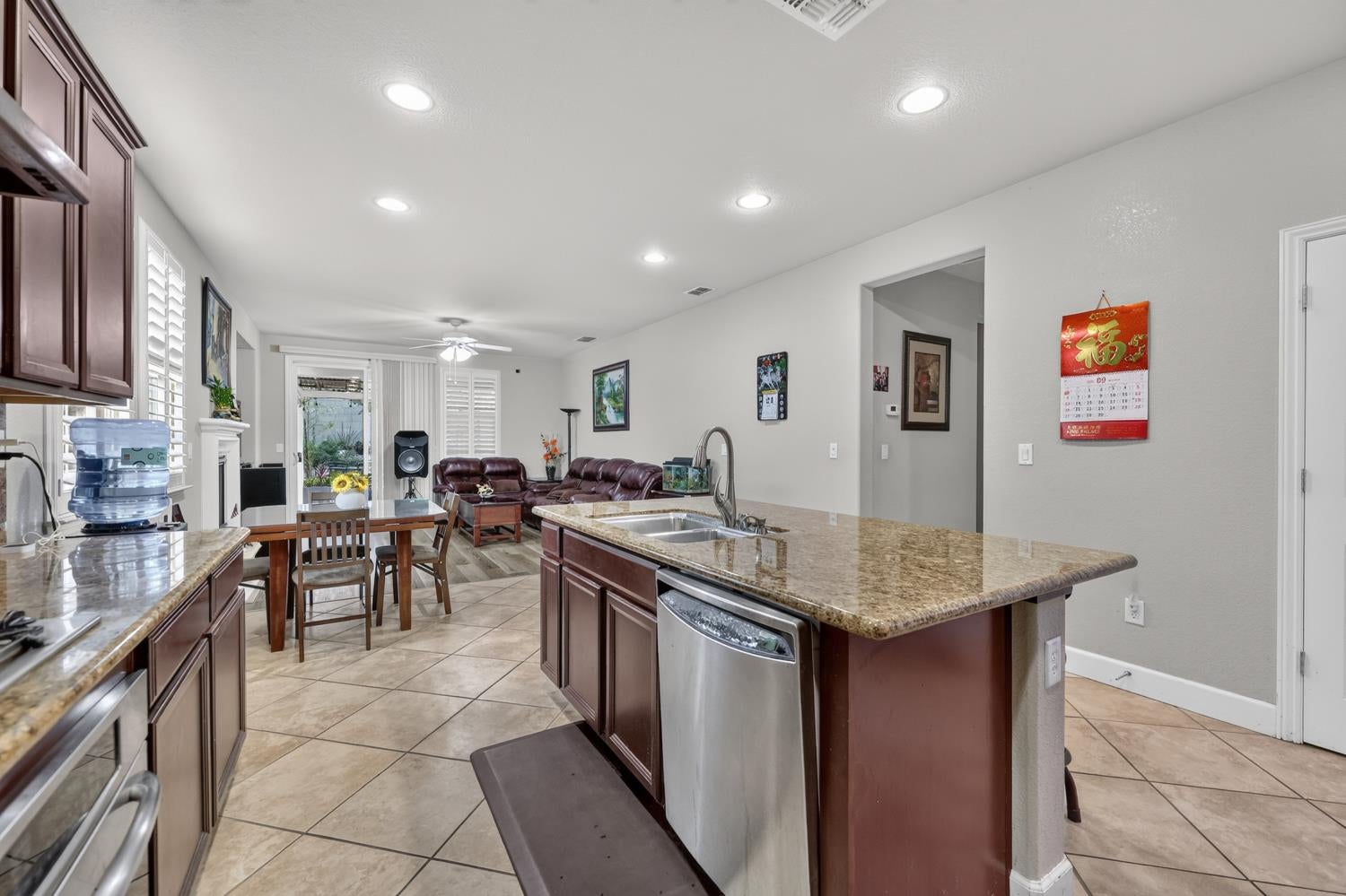 Kitchen island with granite counters and dark cabinets overlooking a dining and living area.