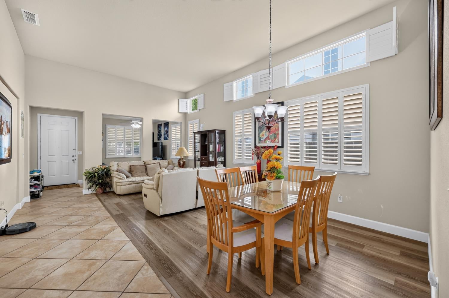 Open living and dining room with vaulted ceiling and plantation shutters.