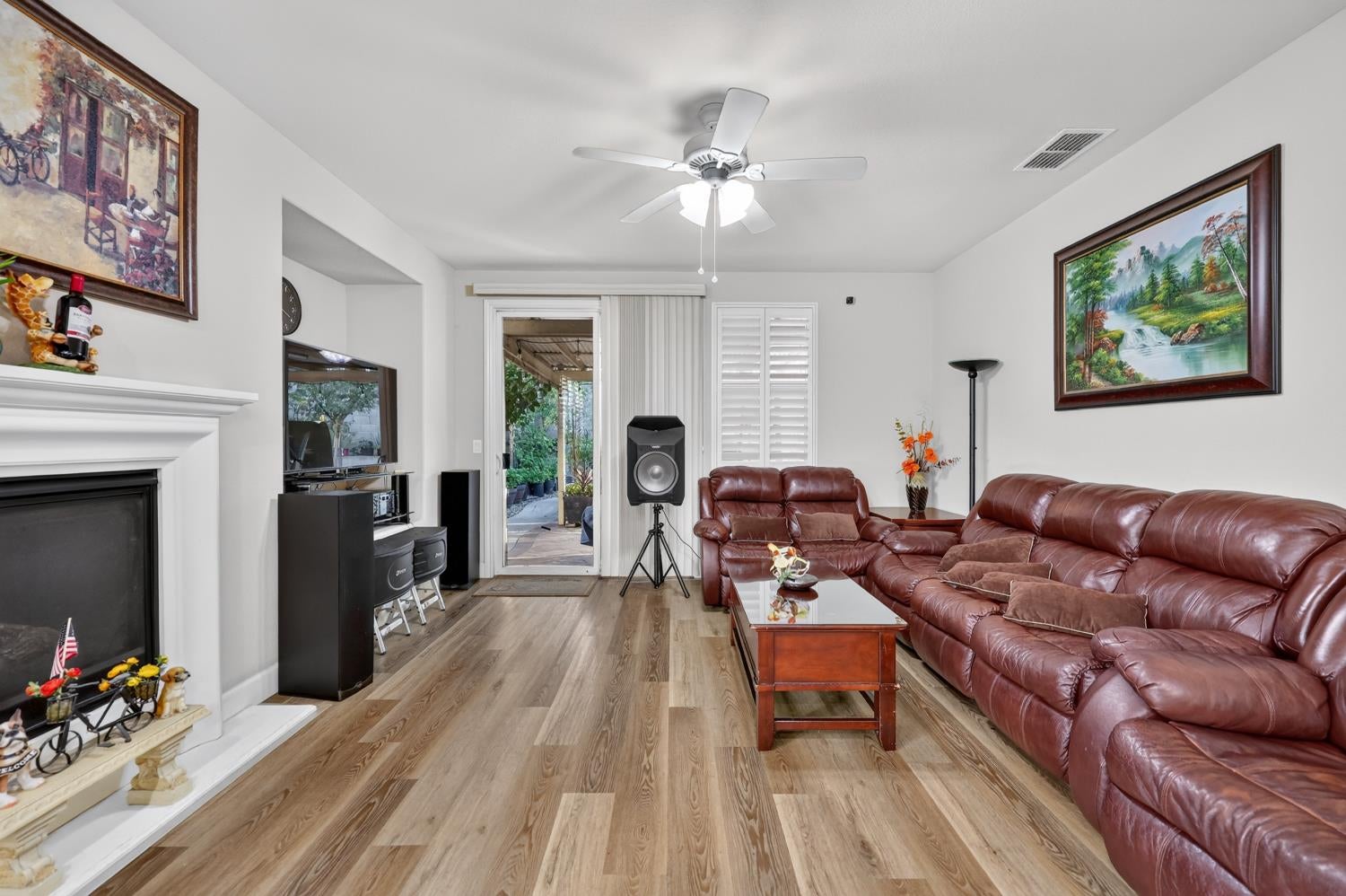 Living room with burgundy leather sofas, a white fireplace, and a sliding door to the patio.