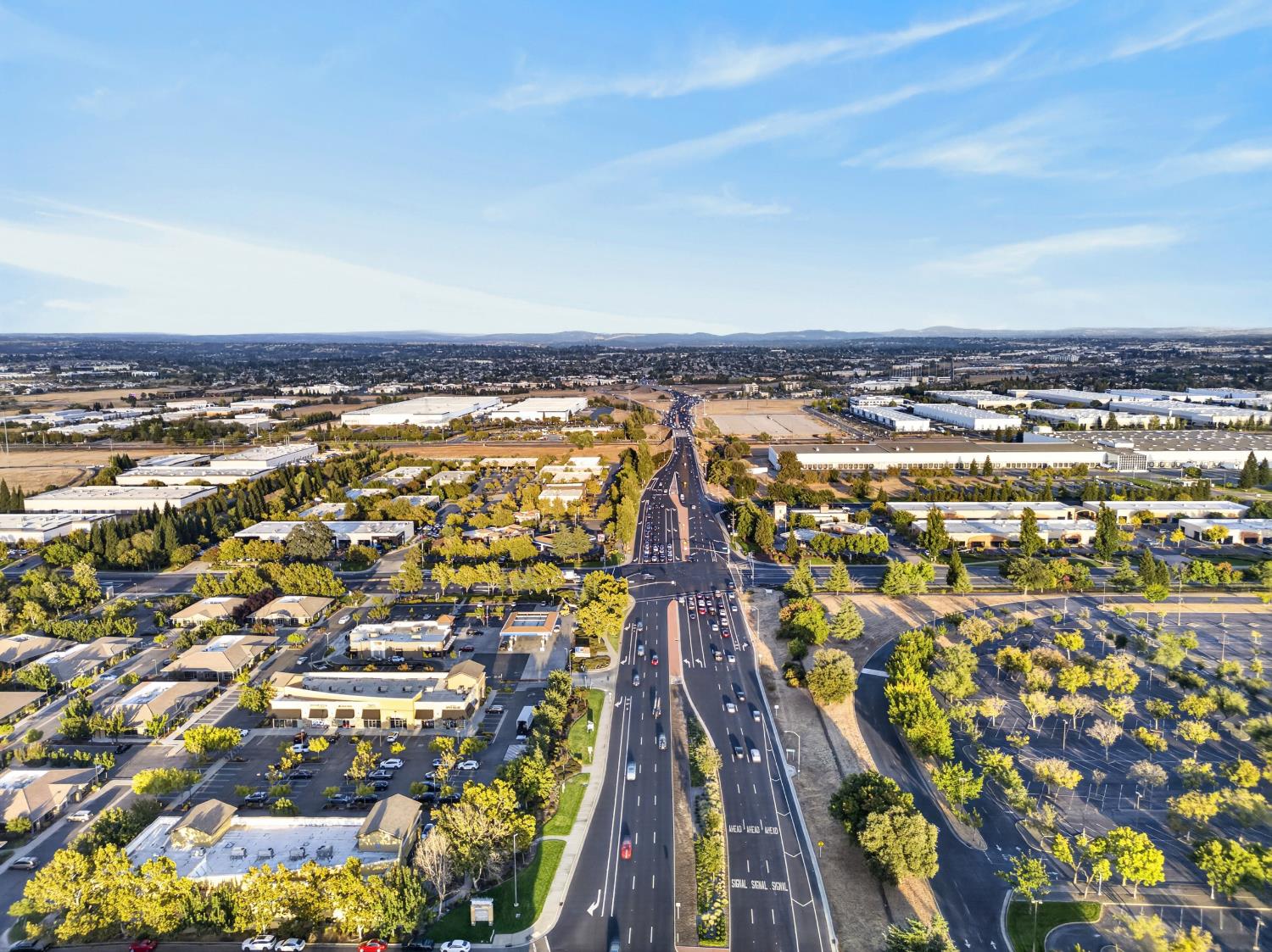 Aerial view of a suburban commercial district with a multilane highway and rows of warehouses.