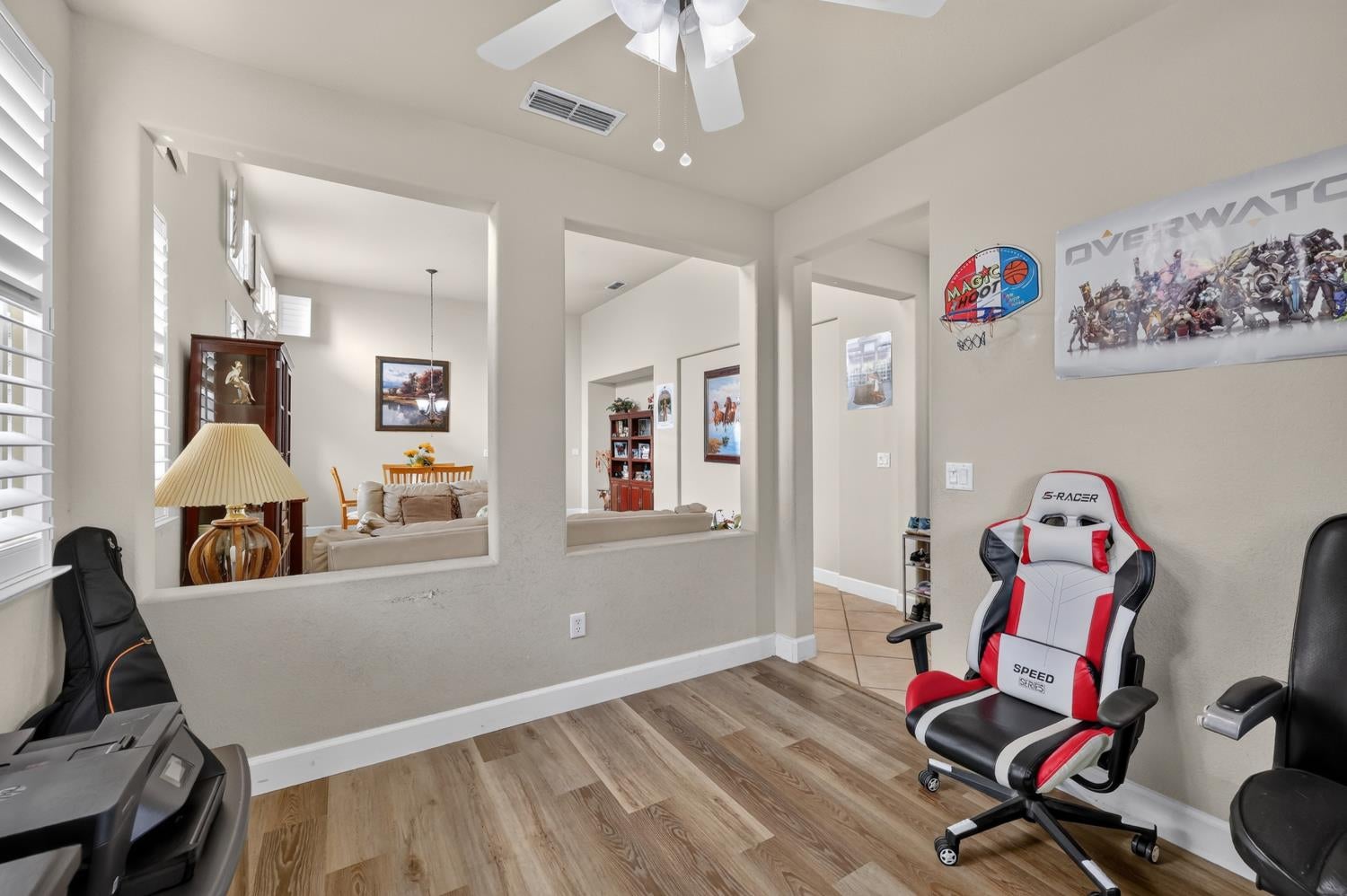 Home office with a red-and-white gaming chair and openings overlooking the living and dining area.