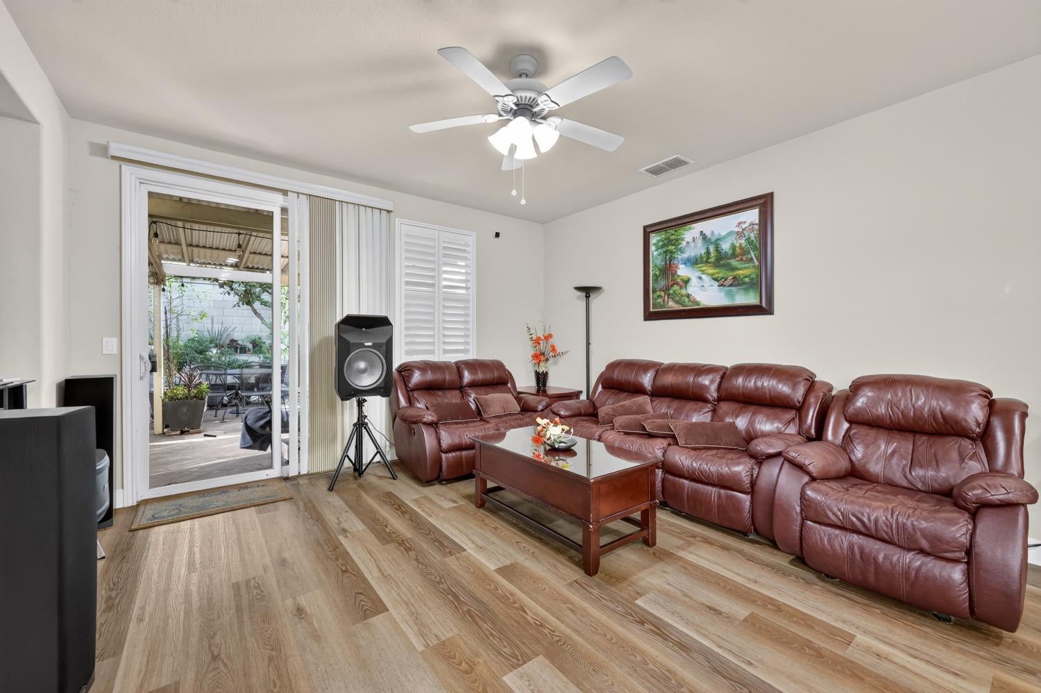 Living room with leather reclining sofas, a glass-top coffee table, and a sliding door to the patio.