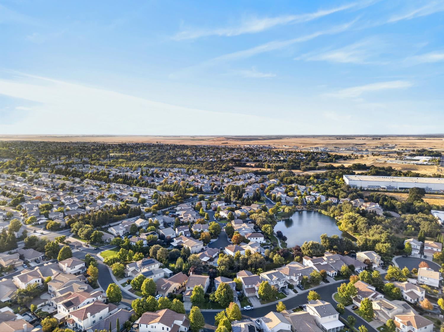 Aerial view of a Roseville neighborhood with a lake and open fields beyond.