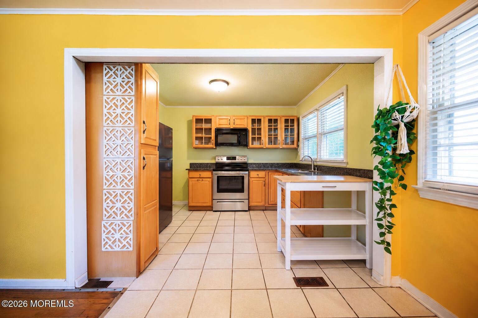 Kitchen with honey-colored cabinets, stainless steel appliances, and a white worktable.