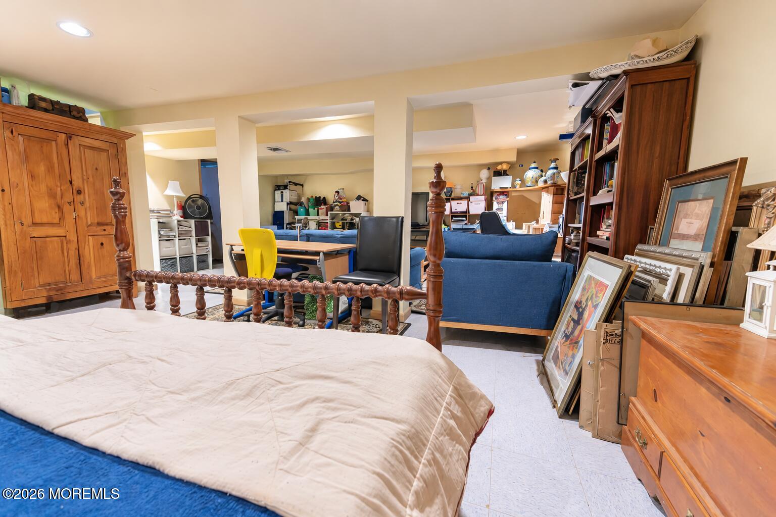 Furnished room with a bed, blue sofas, a dining table, and wooden cabinets.