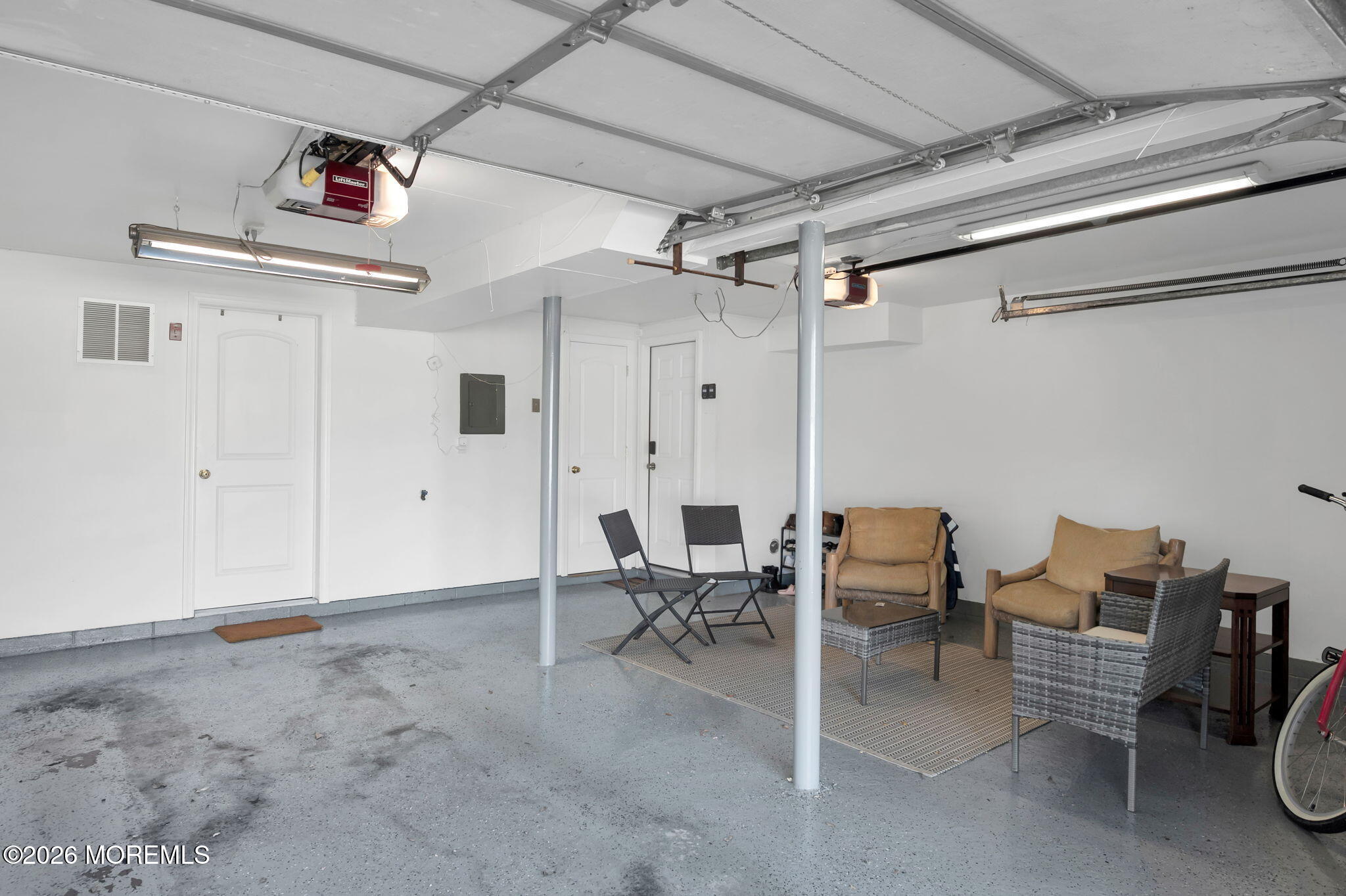 Garage with a seating area, overhead door, and gray concrete floor.