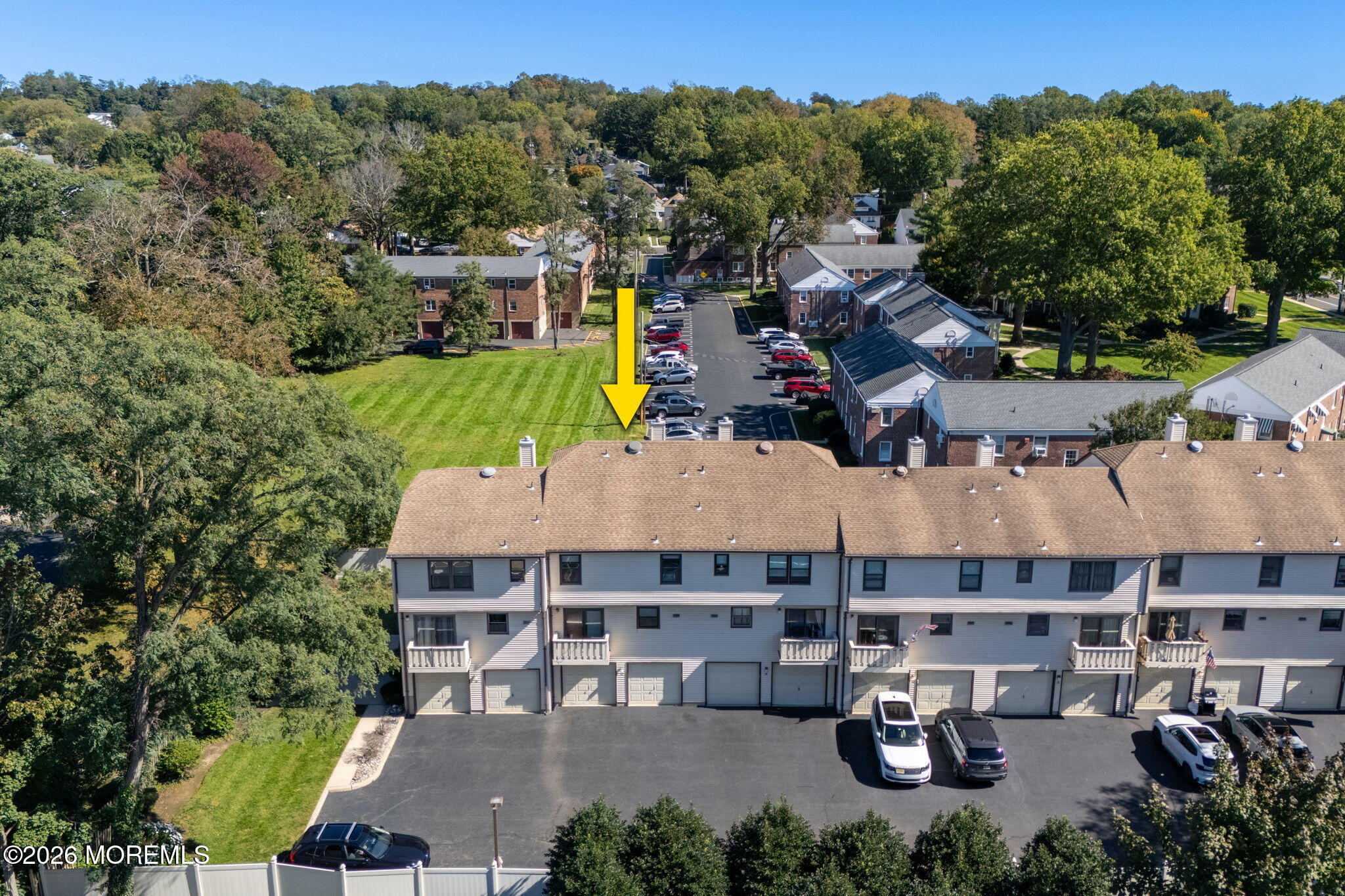 Aerial view of attached homes, with a yellow arrow marking one unit beside the parking lot.
