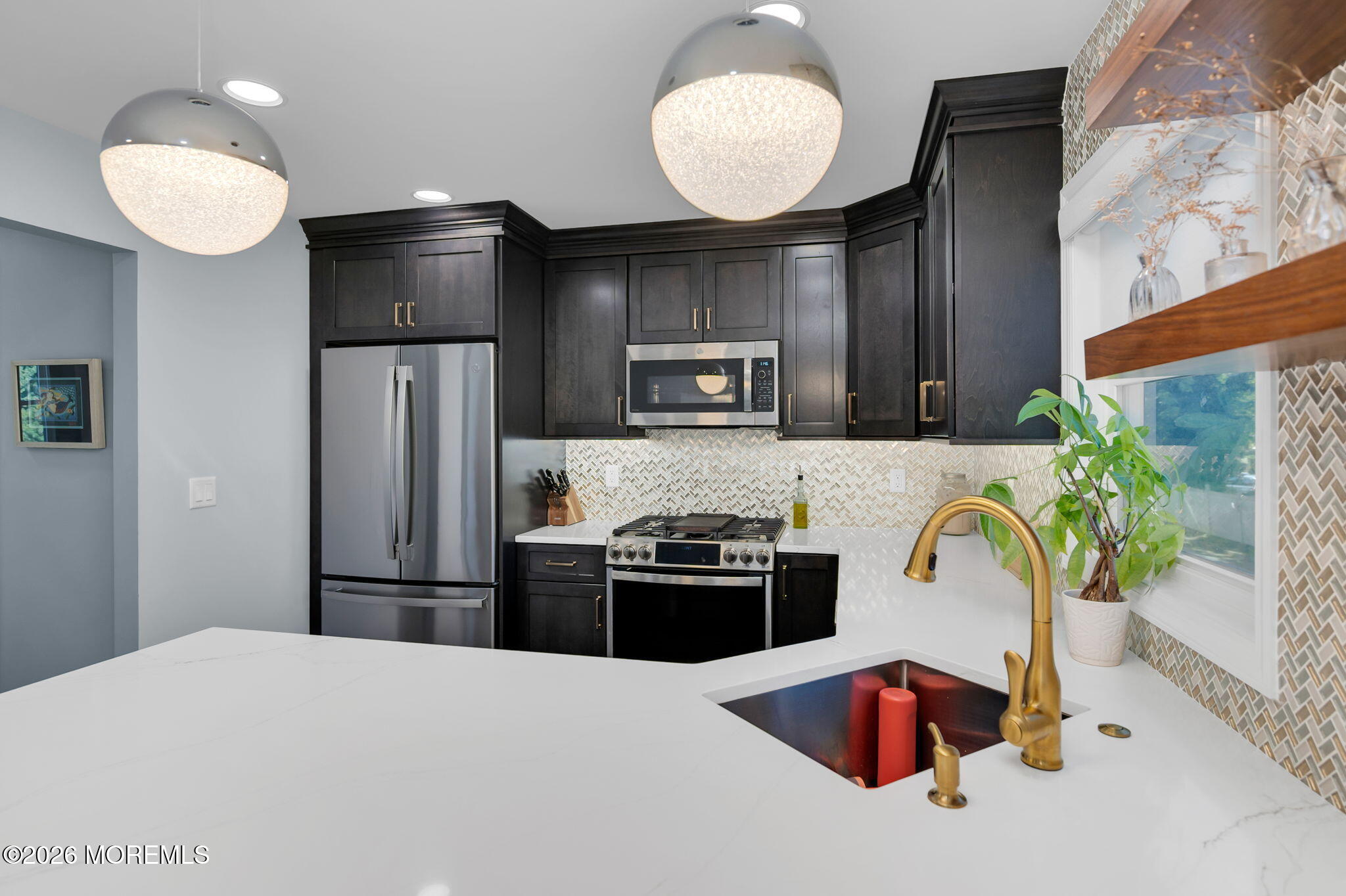 Modern kitchen with dark cabinetry, patterned tile backsplash, and a white island with brass faucet.