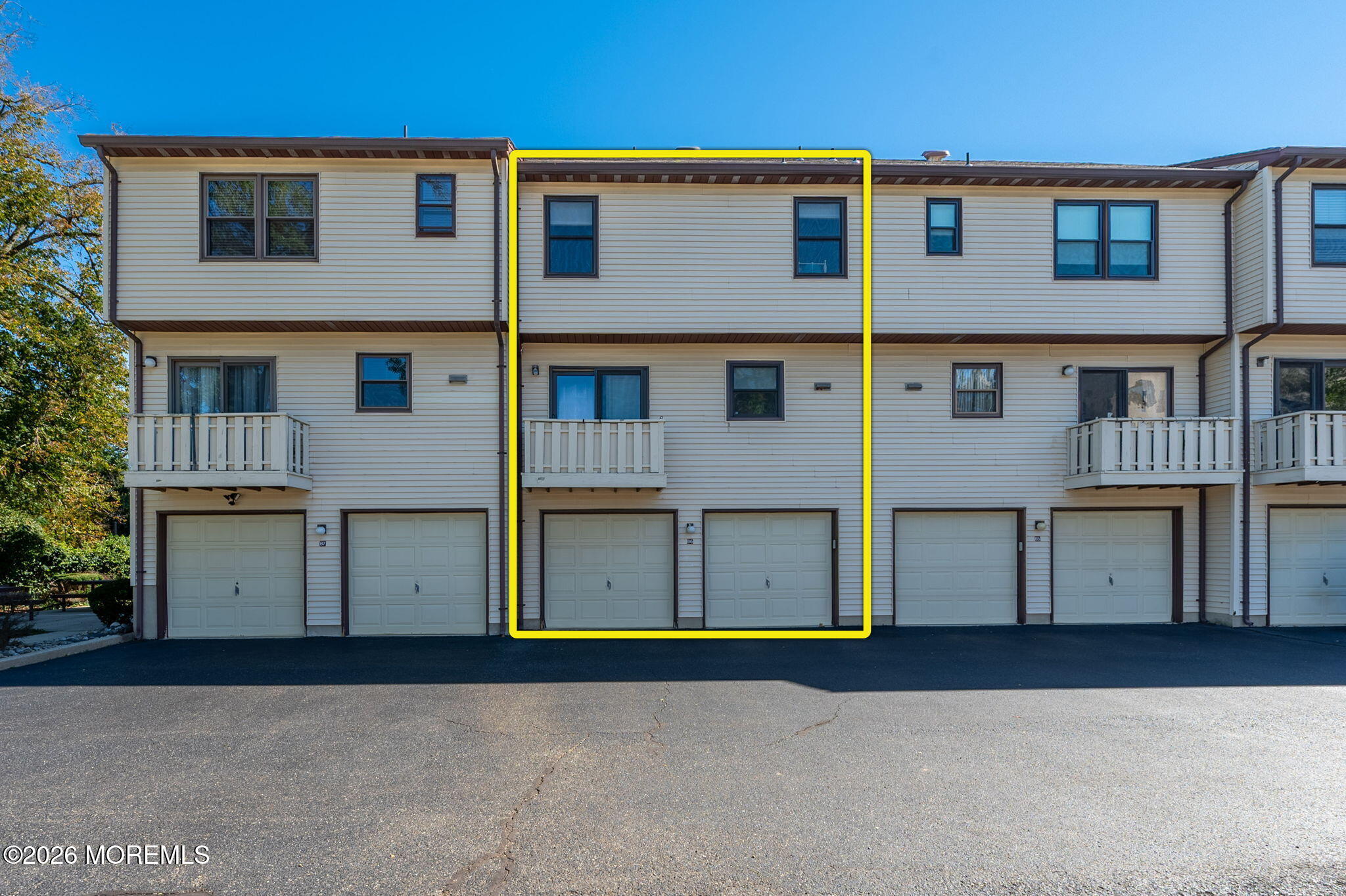 Townhouse unit outlined in yellow, with a small balcony and two garage doors.