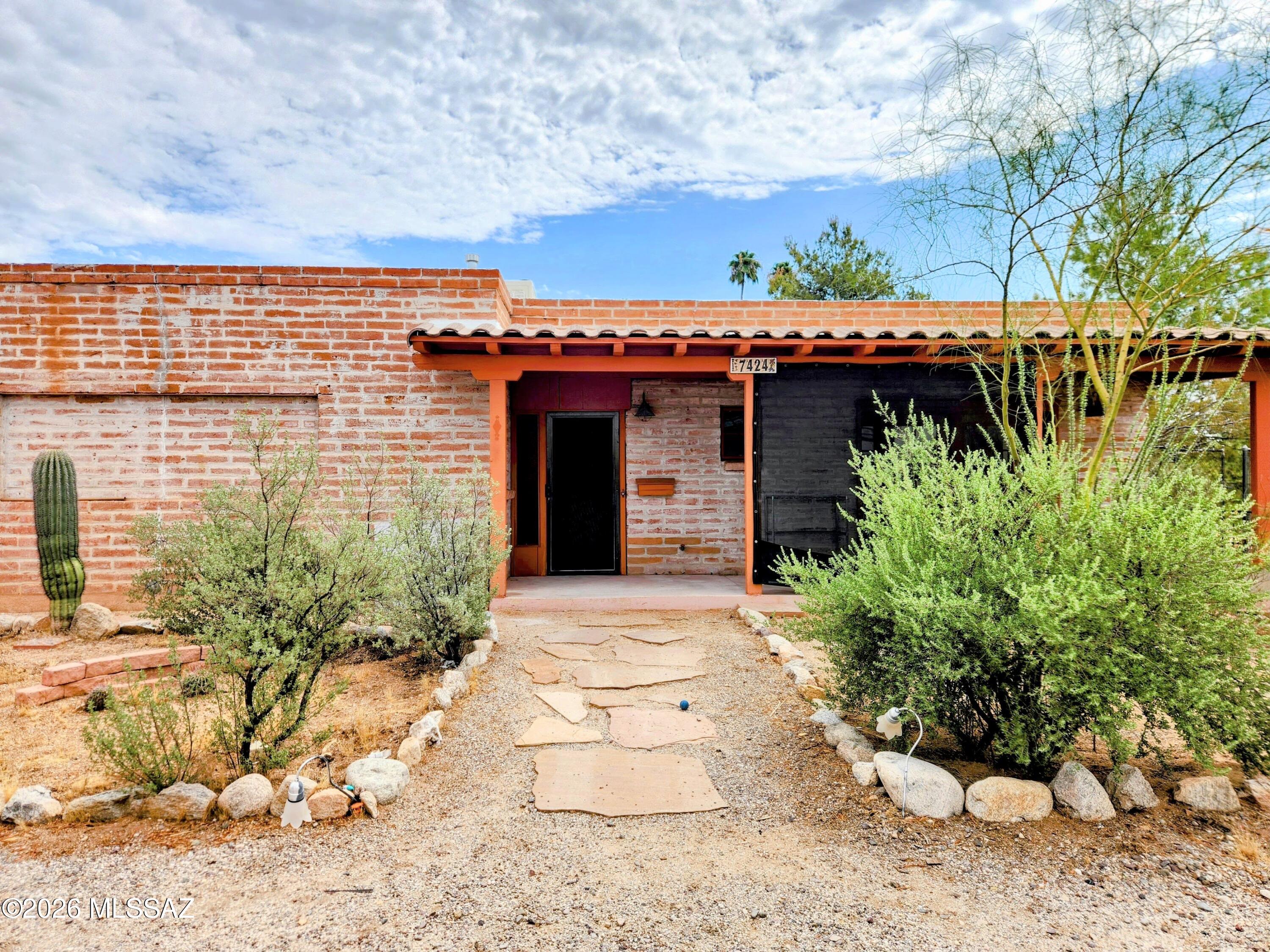 Tucson home with a brick facade, covered entry, and desert landscaping.
