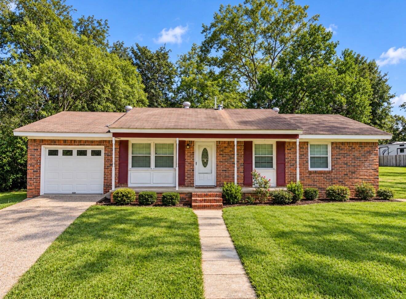 Single-story brick ranch house with an attached garage, front porch, and green lawn.