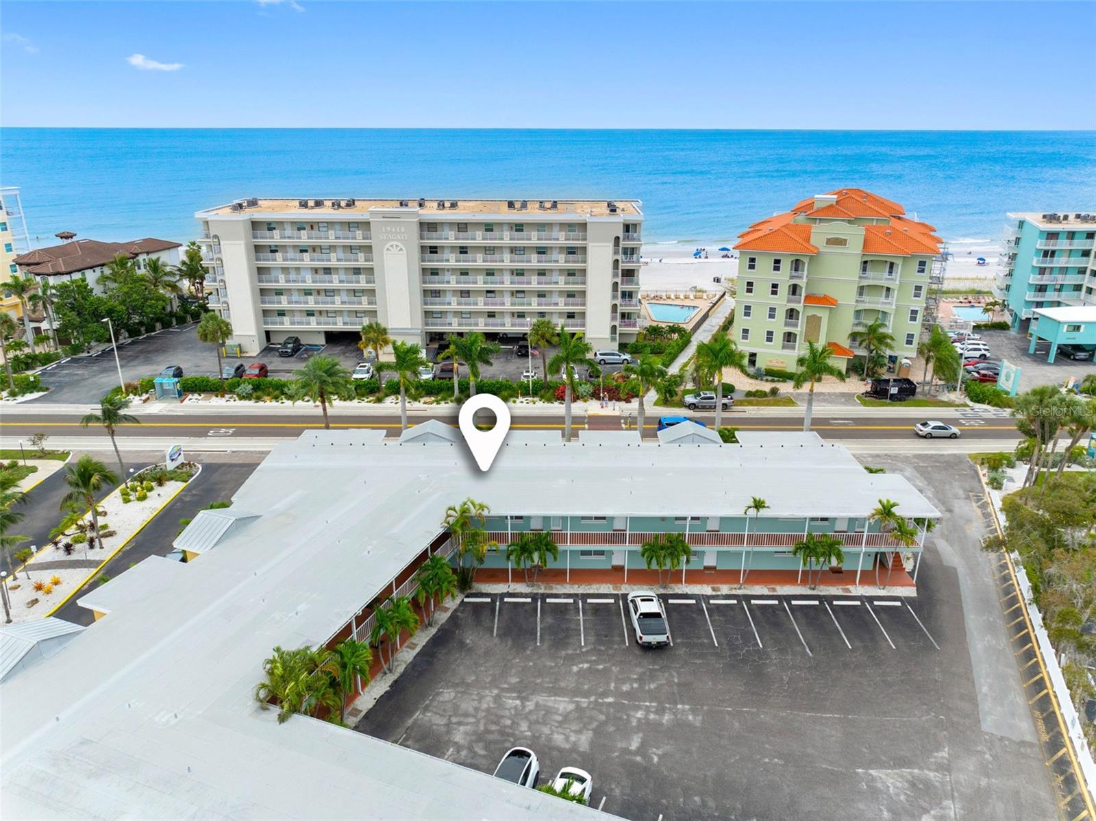 Aerial view of a beachfront condominium complex, with the ocean and neighboring buildings beyond Gulf Boulevard.