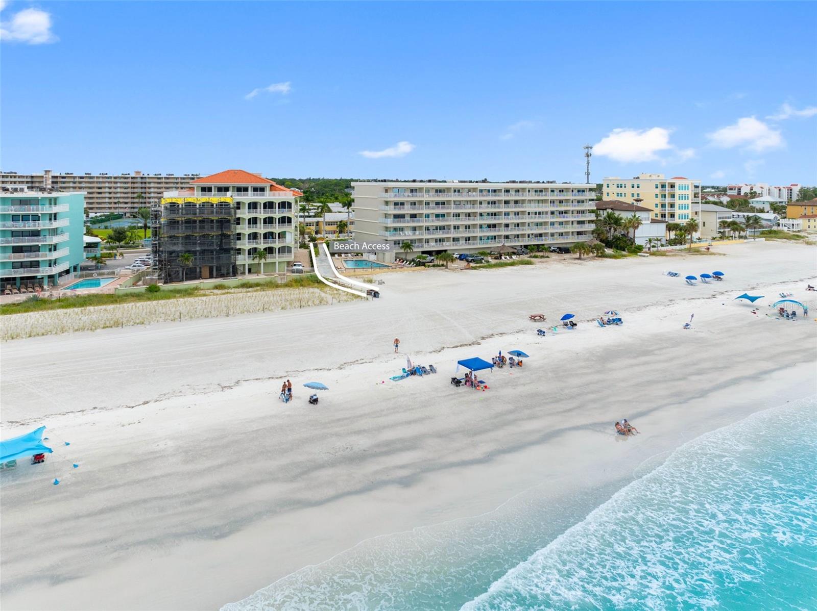 Aerial view of beachfront condominiums and beach access along a wide sandy shore.