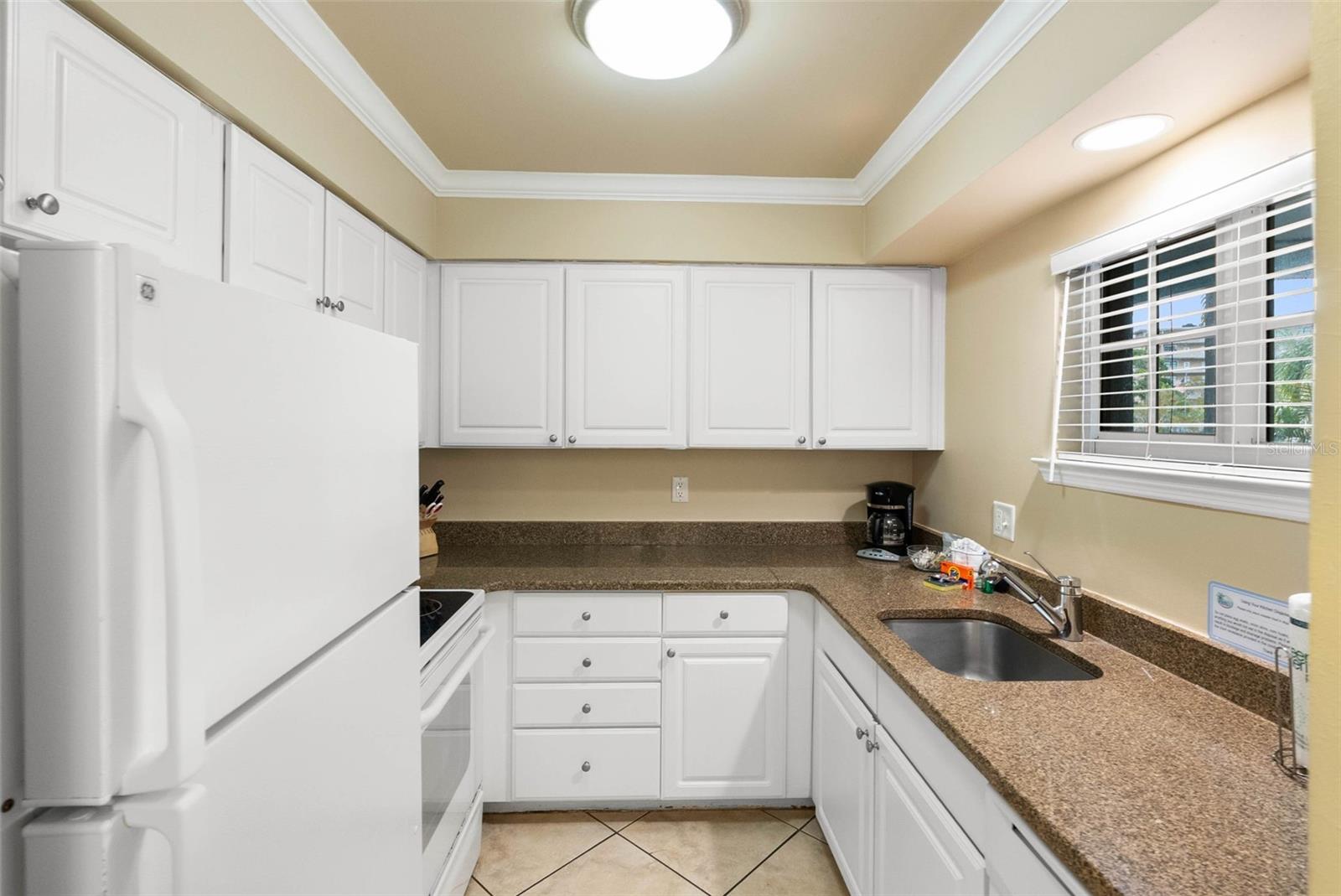 Kitchen with white cabinets, brown countertops, and a window above the sink.
