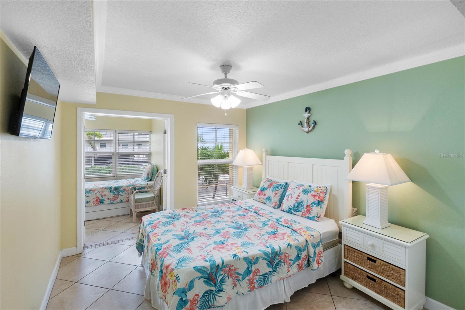 Bedroom with floral bedding, mint-green accent wall, and adjoining window seat.