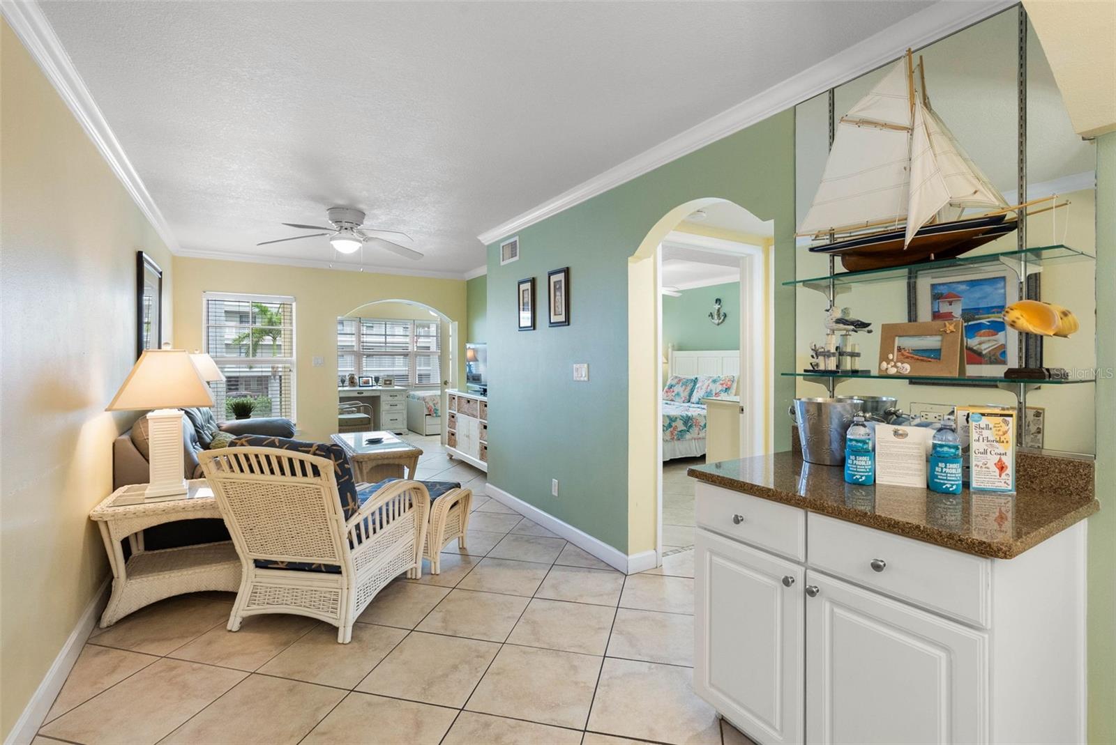 Furnished living room with wicker seating, tiled floors, and a decorative sailboat display.