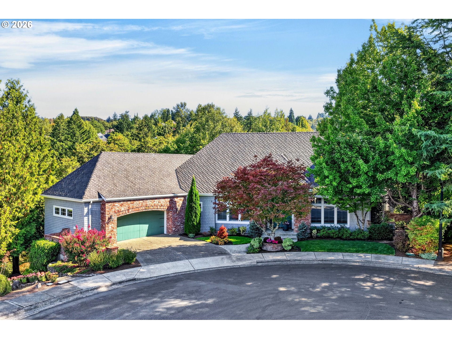 Suburban home with a brick-arched garage, green door, and landscaped front yard.
