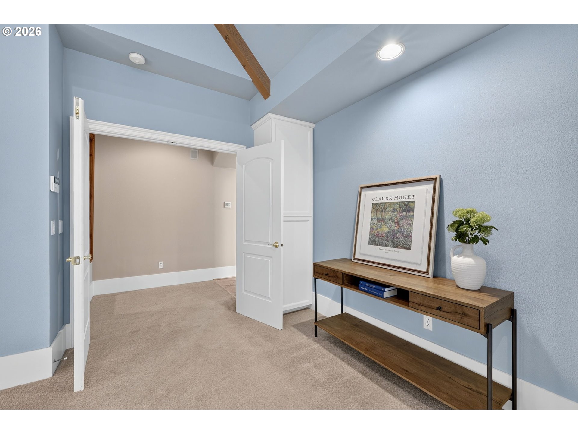 Furnished blue-walled room with a vaulted ceiling, open doors, and a wooden console table.