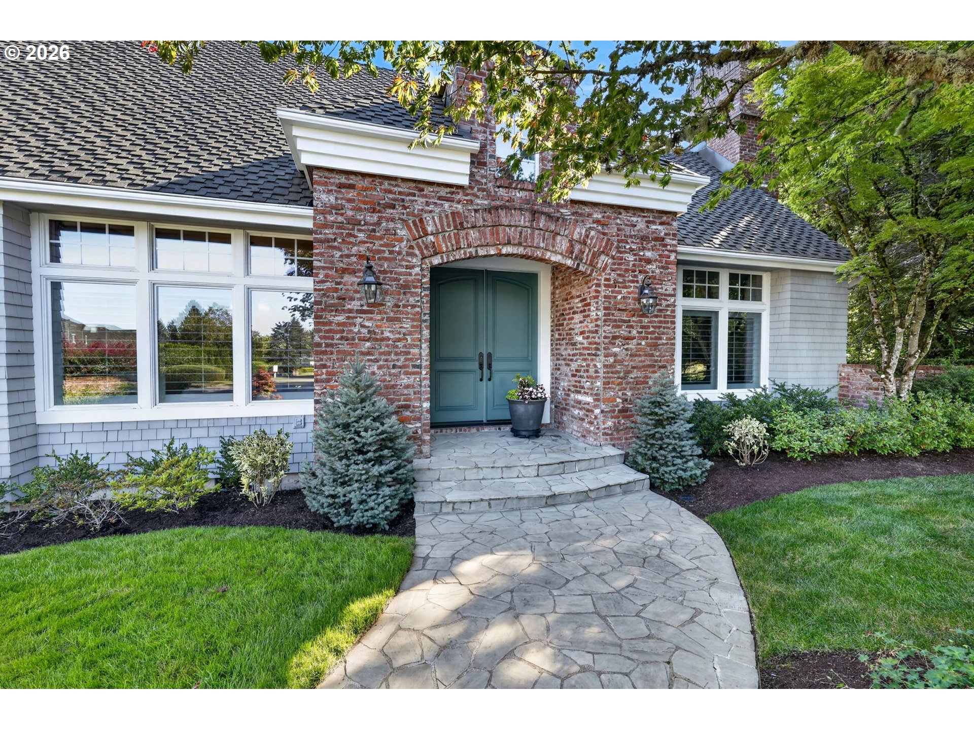 Home exterior with a brick archway, teal double doors, and a curved stone walkway.