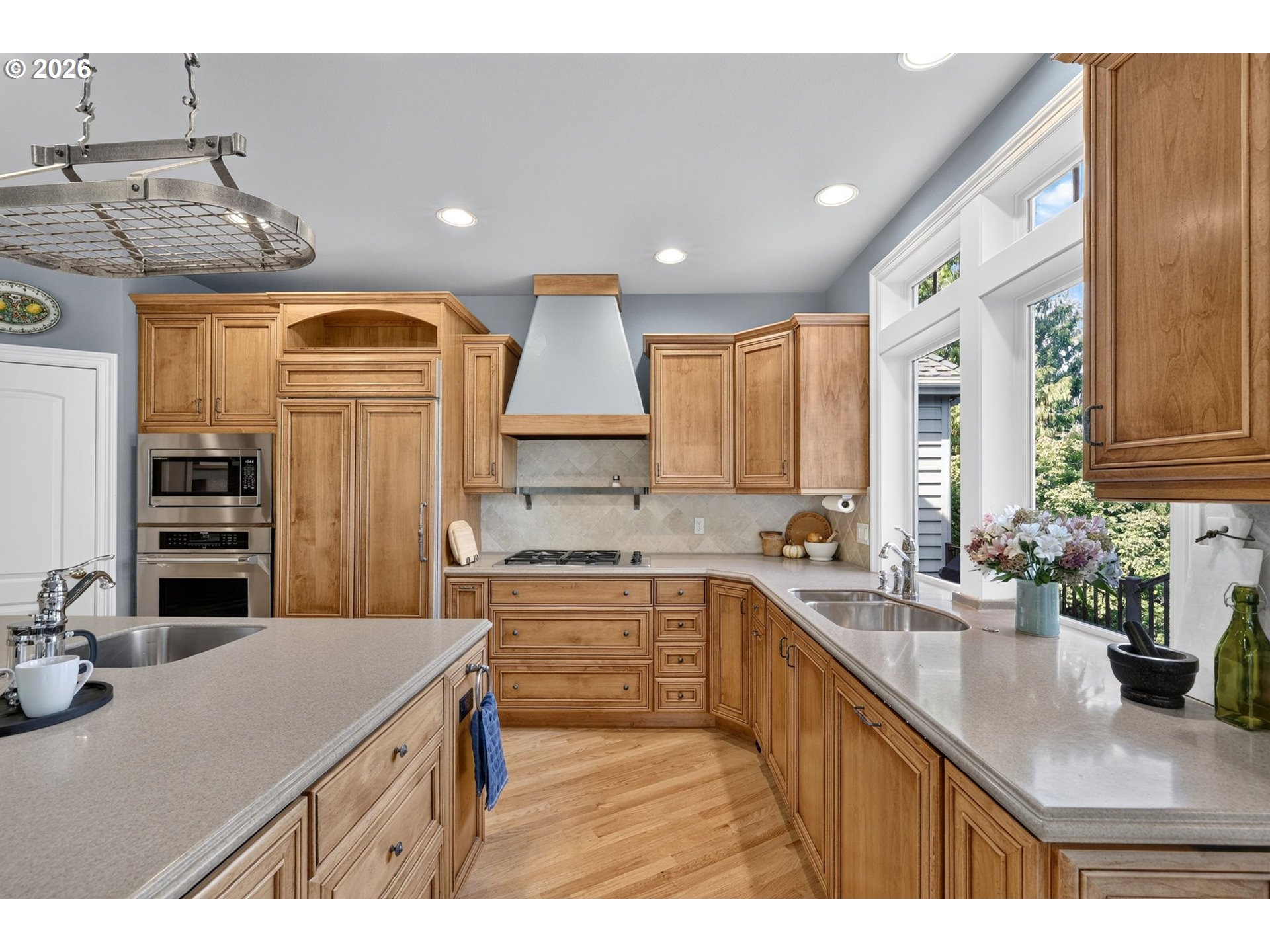 Kitchen with warm wood cabinets, light stone counters, a central island, and large windows.