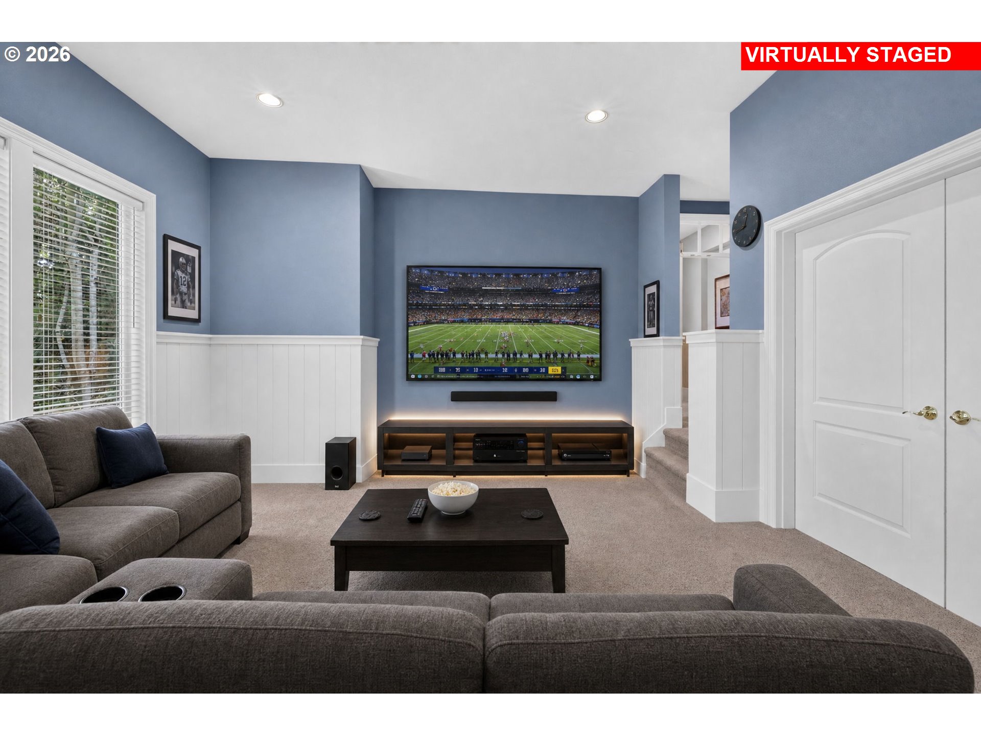 Media room with a large television, sound system, and gray sectional seating.
