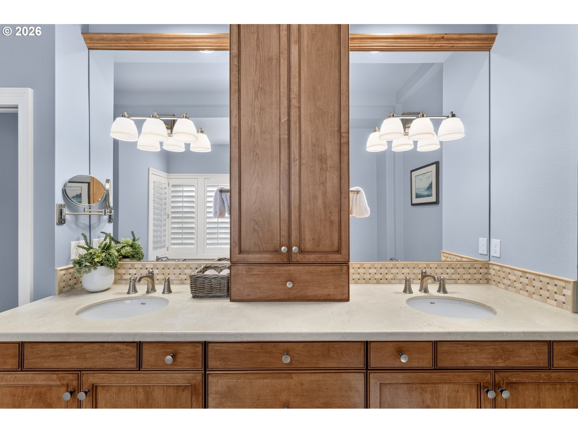 Double-sink bathroom vanity with warm wood cabinets, a stone countertop, and a large mirror.