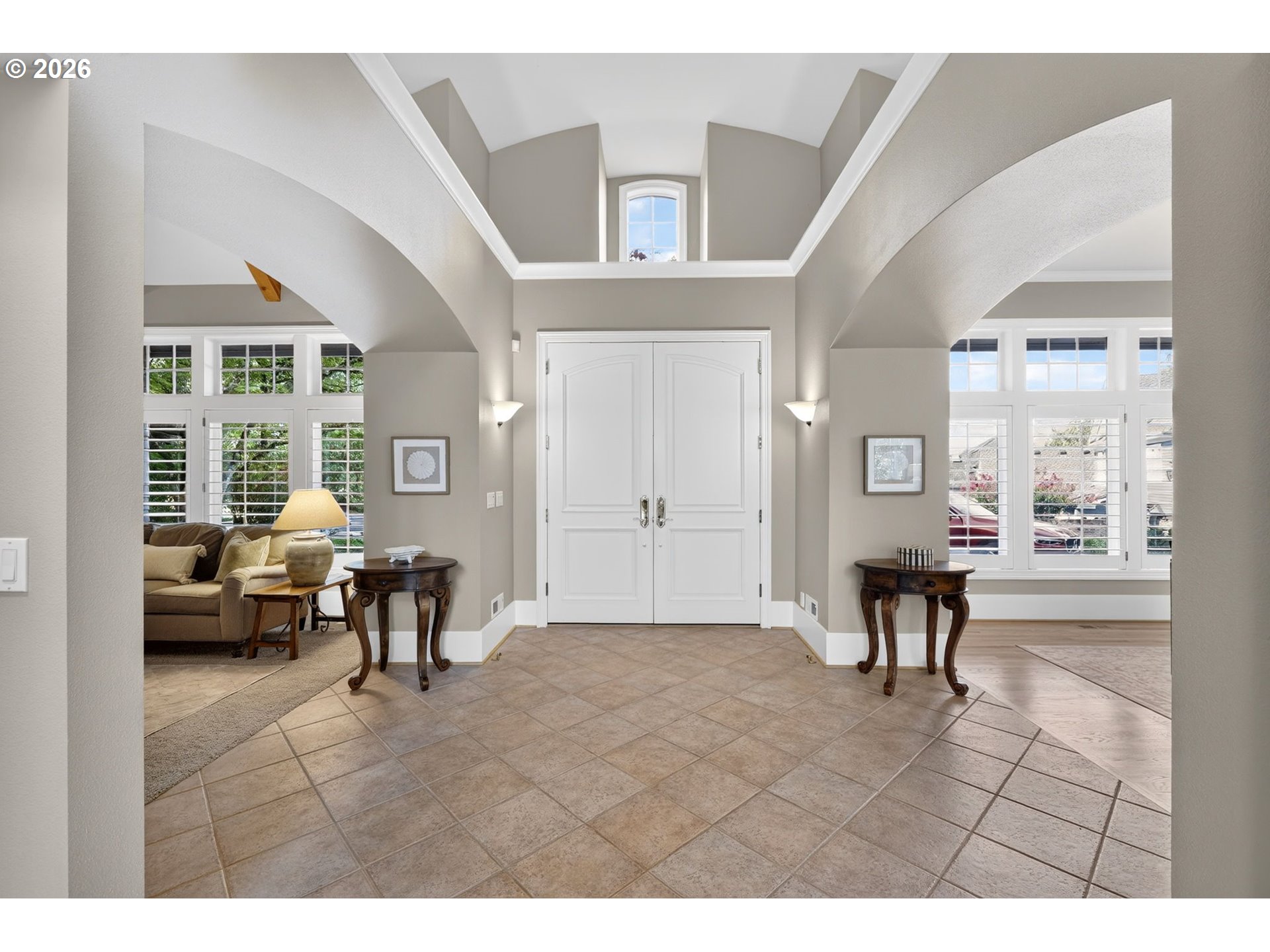 Entry foyer with white double doors, curved ceiling arches, tiled floor, and shuttered windows.