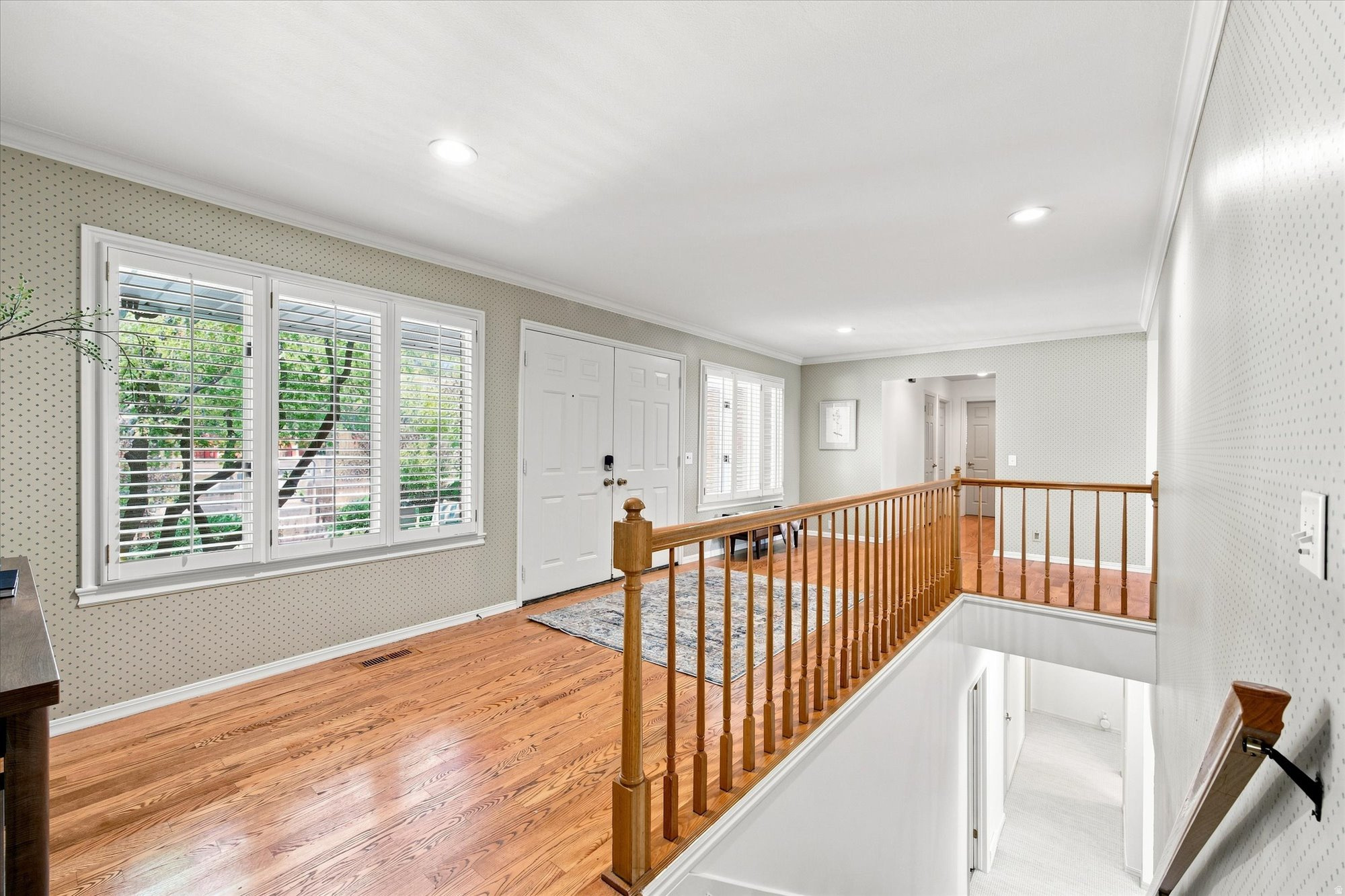 Upper-floor landing with hardwood floors, shuttered windows, and a wooden railing around the stairwell.