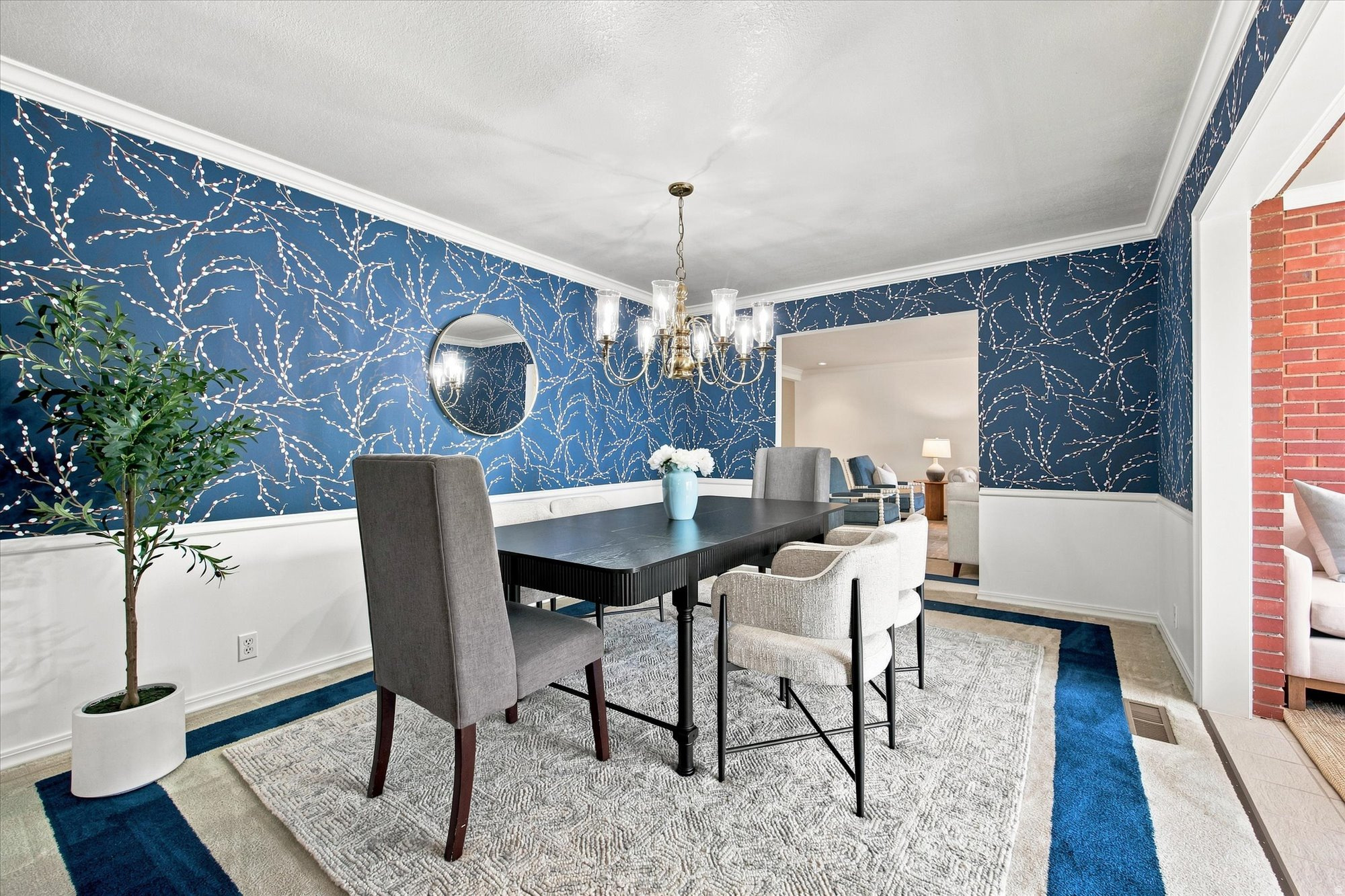 Dining room with navy branch-pattern wallpaper, a dark table, upholstered chairs, and a chandelier.