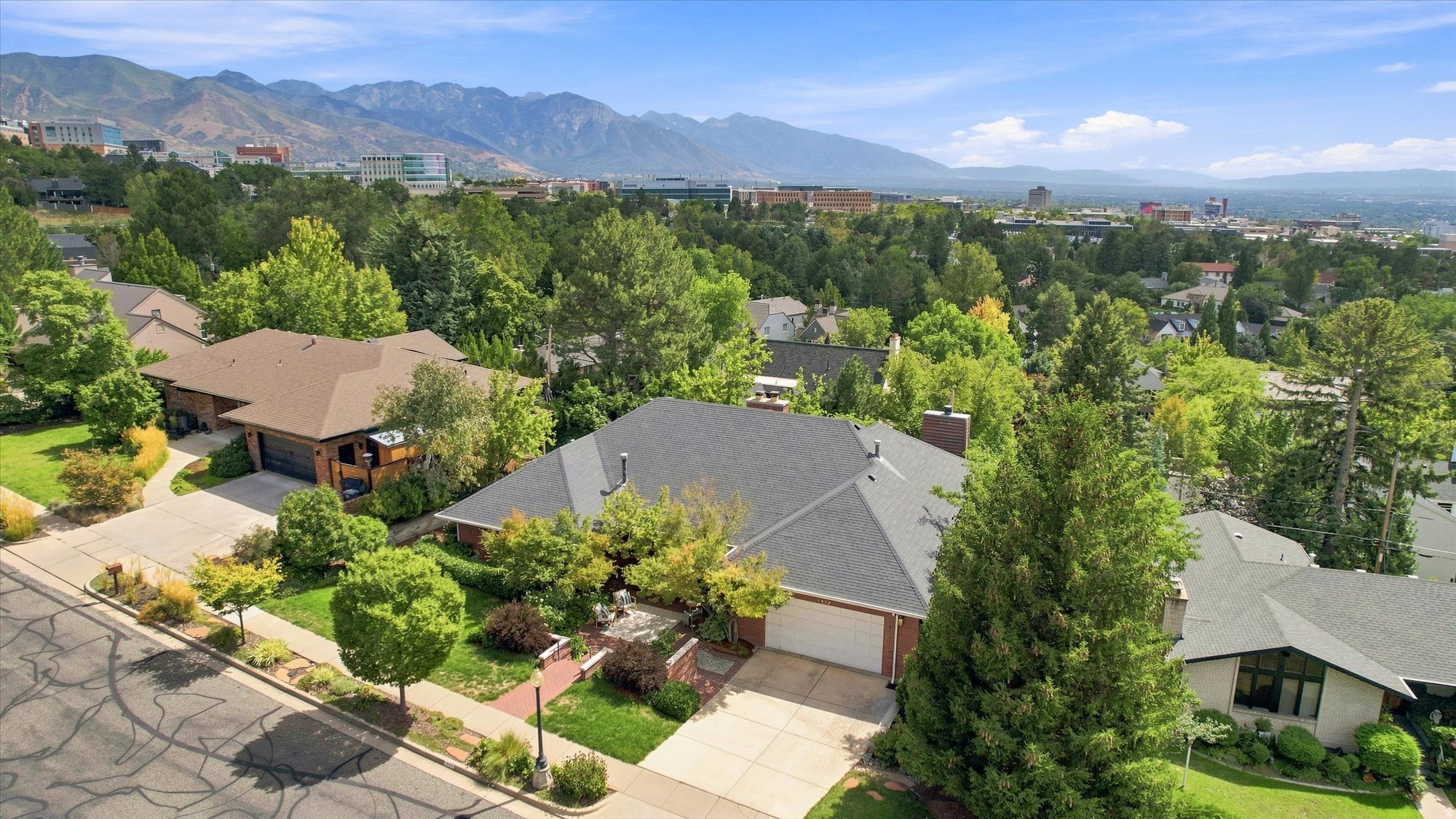 Aerial view of leafy Salt Lake City homes with the Wasatch Mountains in the distance.