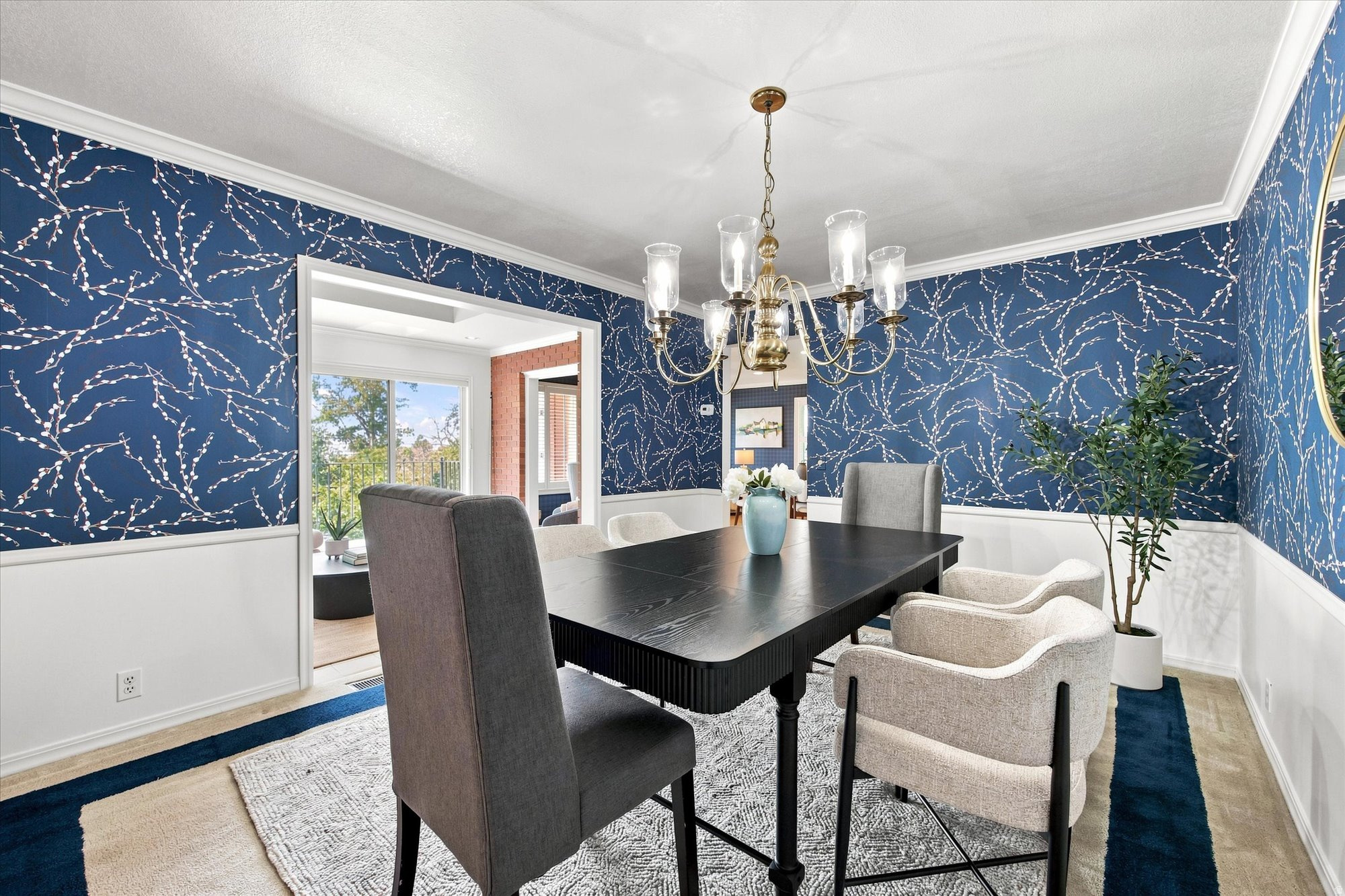 Dining room with navy branch-pattern wallpaper, a black table, upholstered chairs, and a brass chandelier.