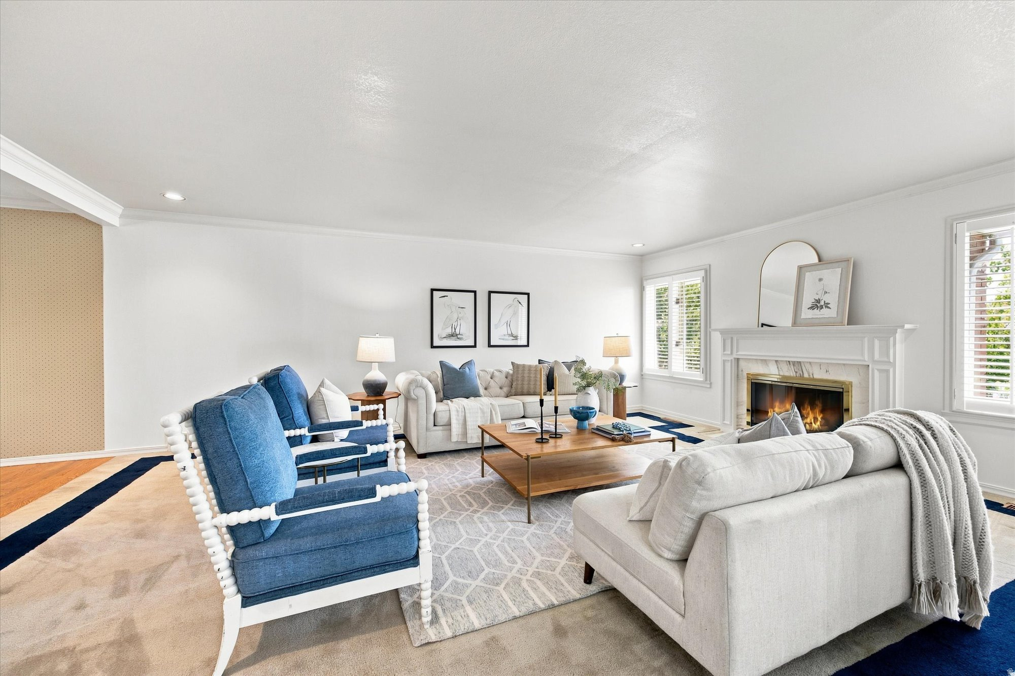 Living room with blue armchairs, white sofas, and a lit fireplace.