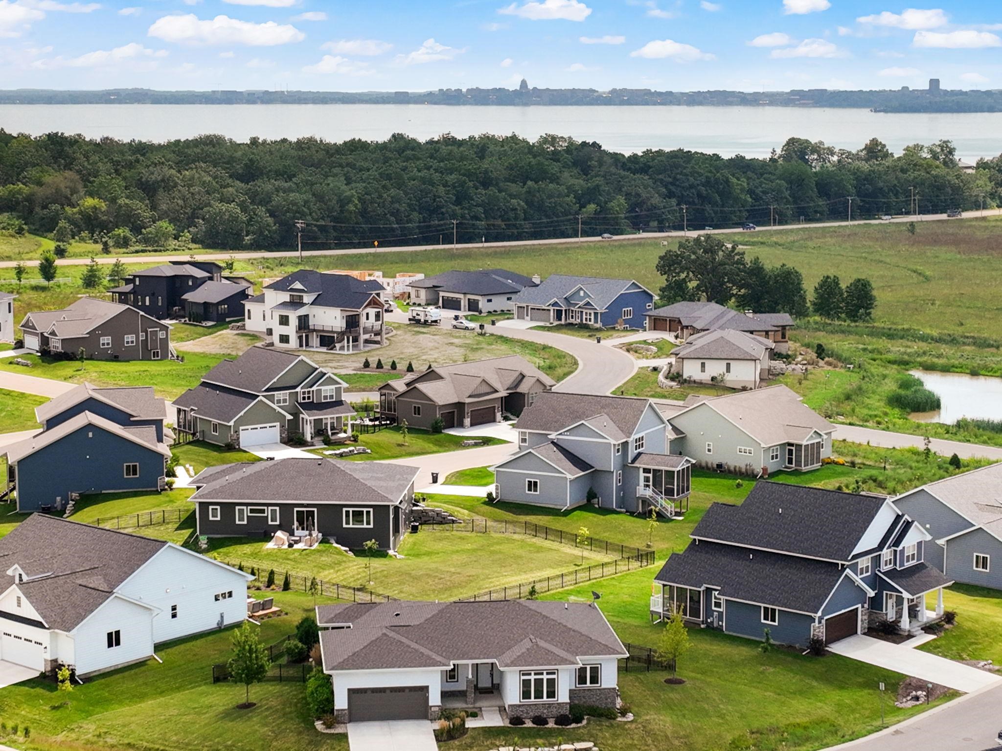 Aerial view of a residential neighborhood beside a lake, with a distant city skyline.