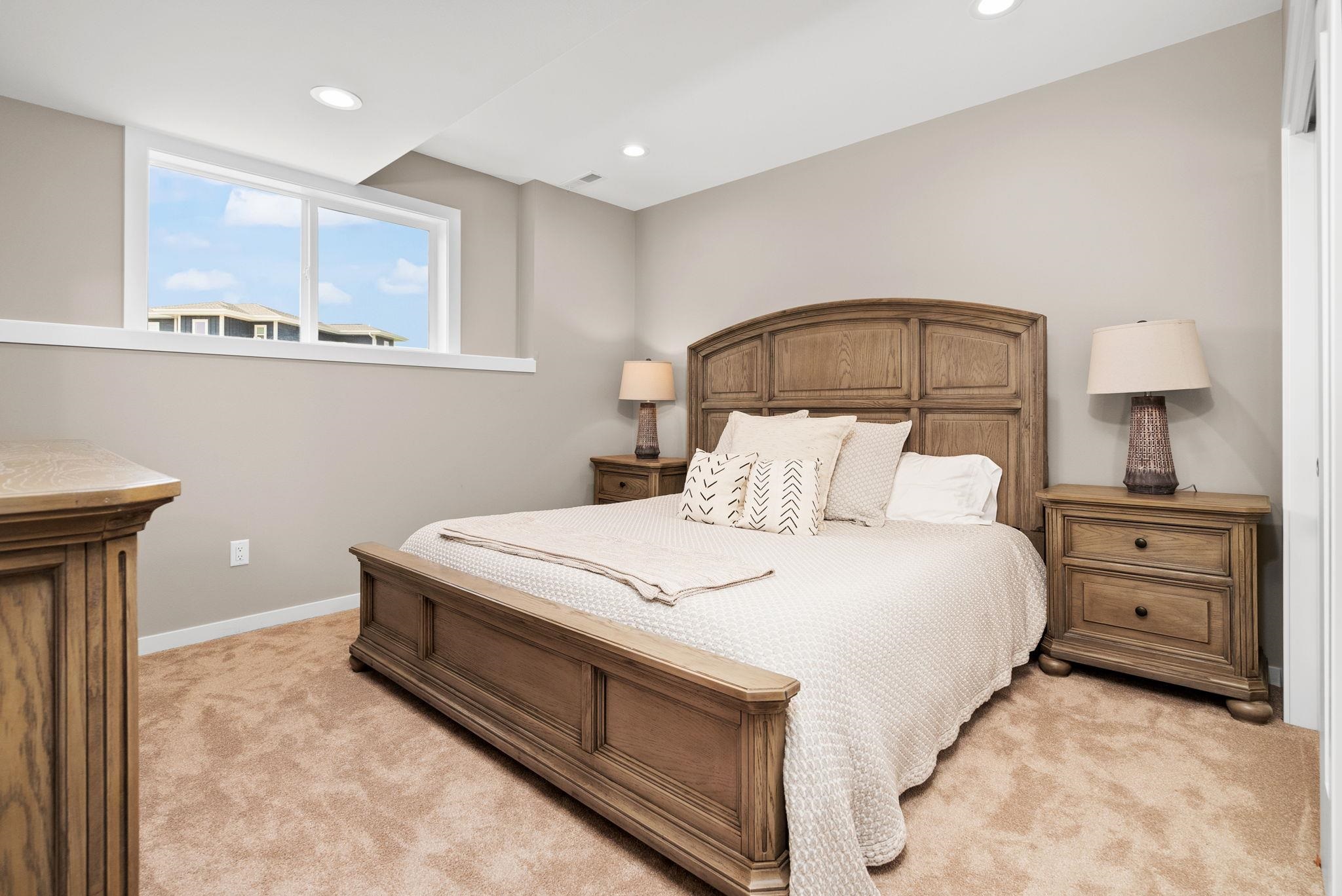 Bedroom with a carved wooden bed, white bedding, matching nightstands, and a high window.