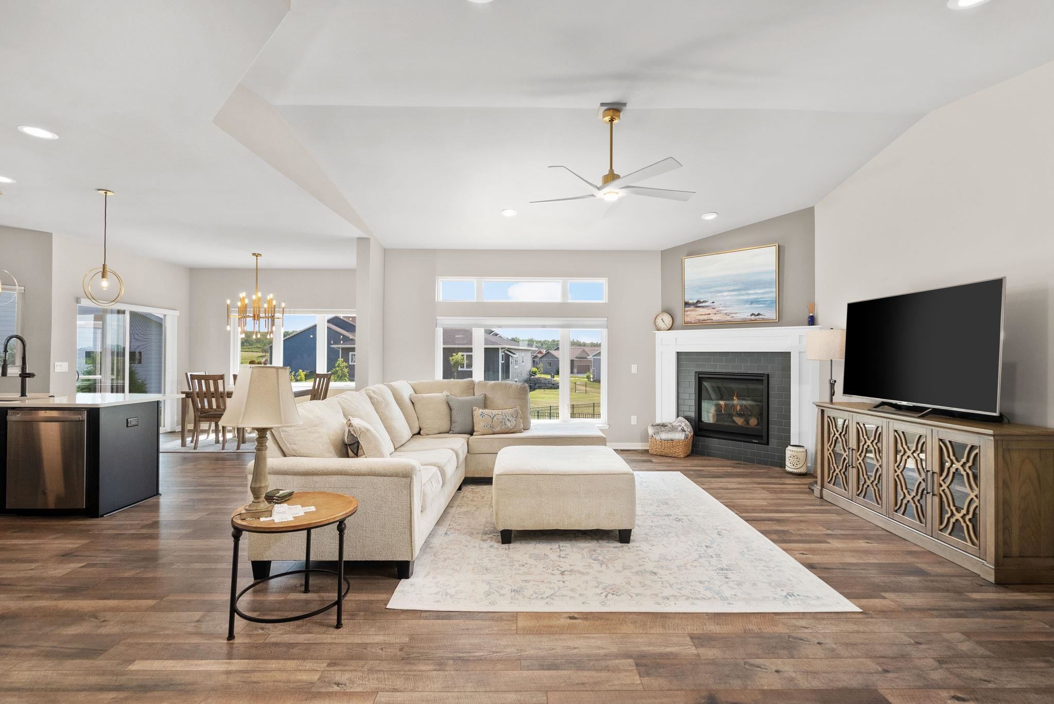 Open-plan living room with a cream sectional, fireplace, and large windows.