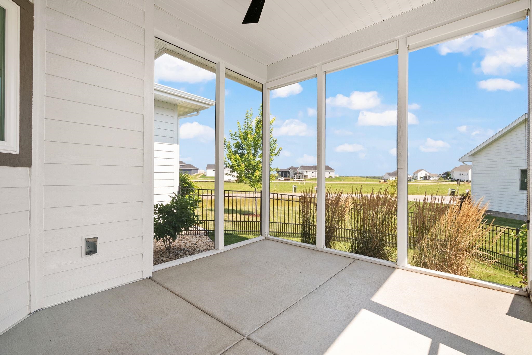 Covered patio with a concrete floor overlooking a fenced lawn and neighboring homes.