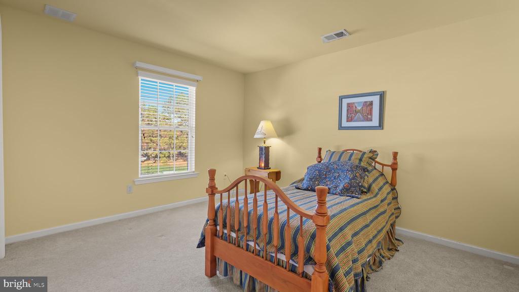 Bedroom with a wooden bed, blue striped bedding, and a window overlooking the yard.