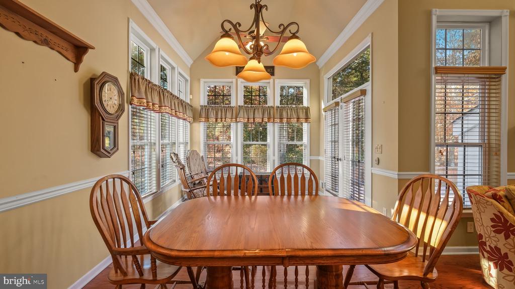 Dining room with a wooden table, chandelier, and windows along three walls.
