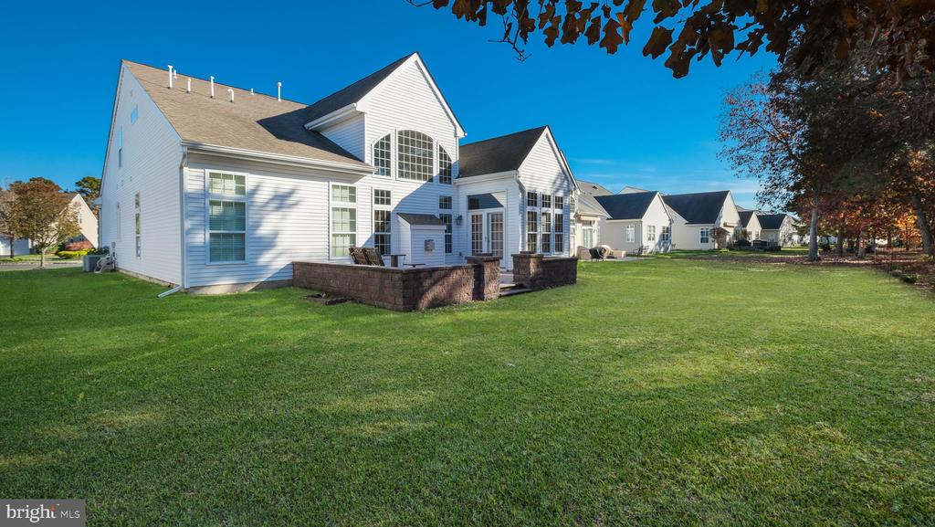 Rear exterior of a white two-story home with a brick patio and broad green lawn.