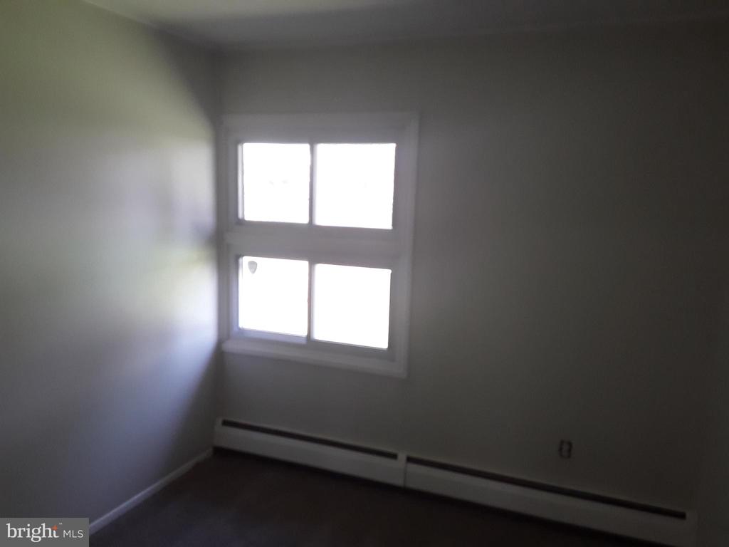 Empty room with a four-pane window and long baseboard heater.