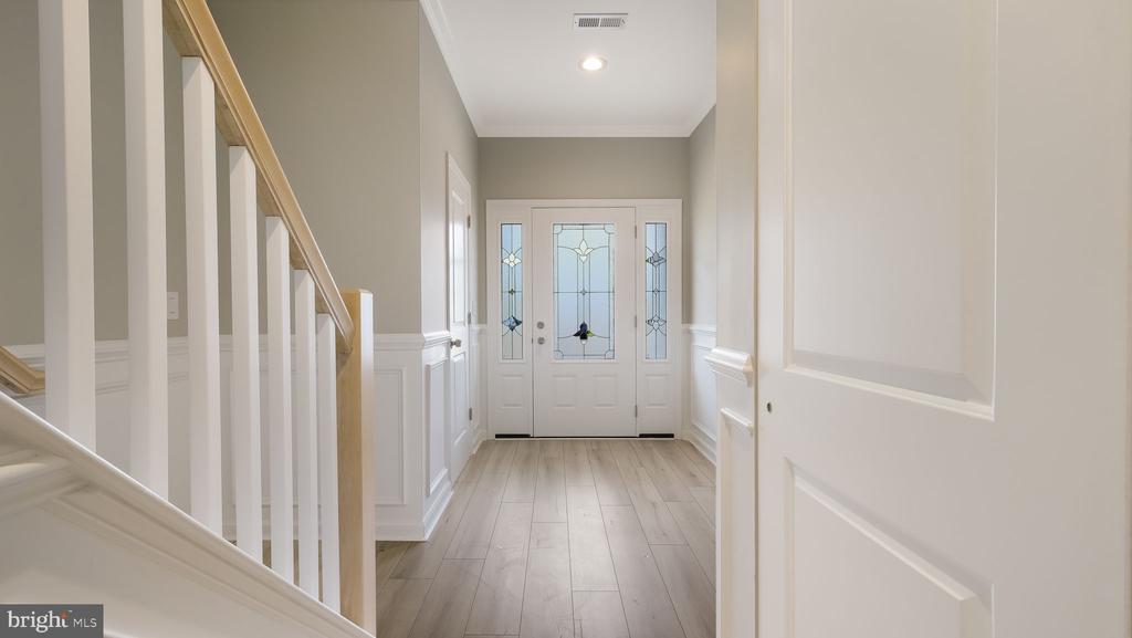 Entry foyer with a white staircase, wainscoting, and decorative glass-panel front door.