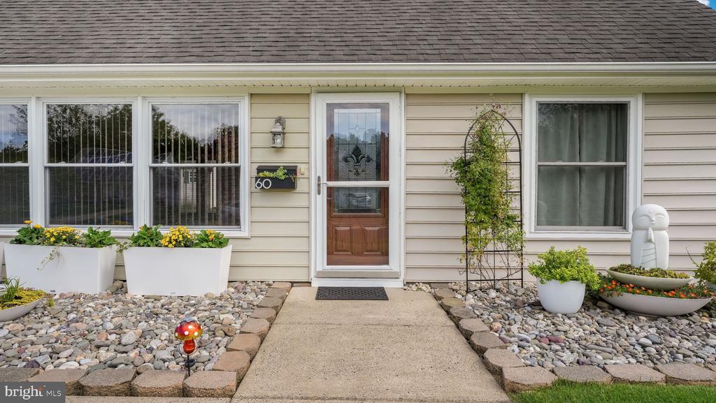 Home entrance with a brown glass storm door, large windows, and landscaped rock beds flanking the walkway.