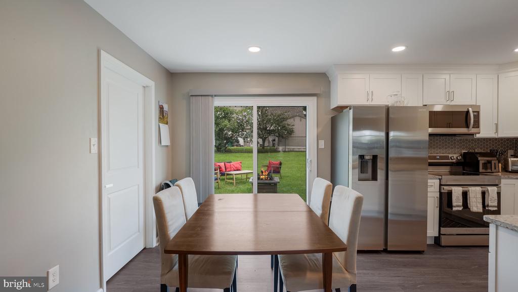Dining area with a wooden table, open kitchen, and sliding doors to the backyard.