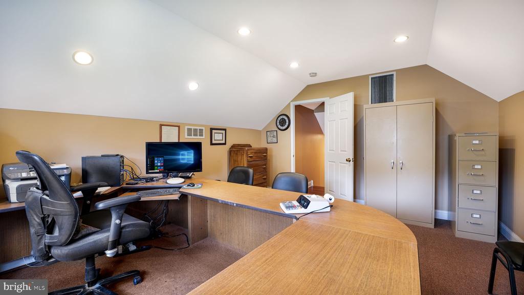 Home office with a curved wooden desk, multiple computer workstations, and storage cabinets.