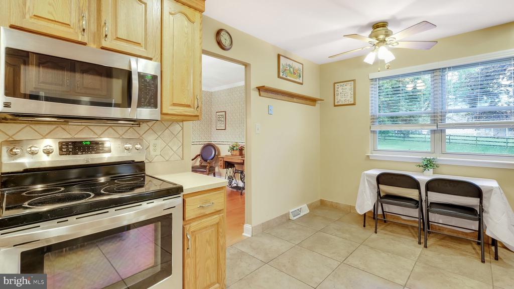 Kitchen with light wood cabinets, stainless steel appliances, and a table beside a wide window.