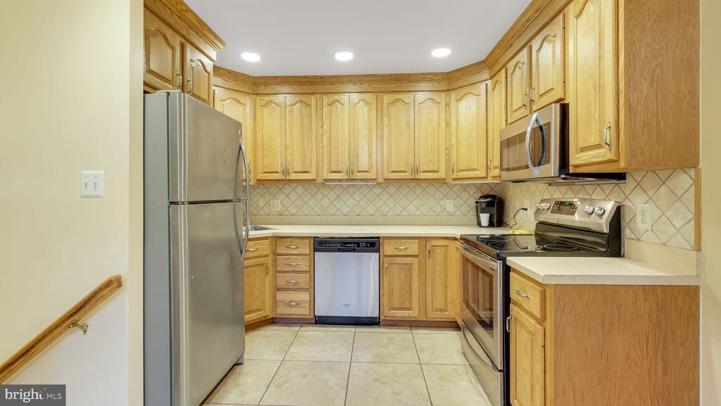Kitchen with honey-colored cabinets, stainless-steel appliances, and a light tile backsplash.