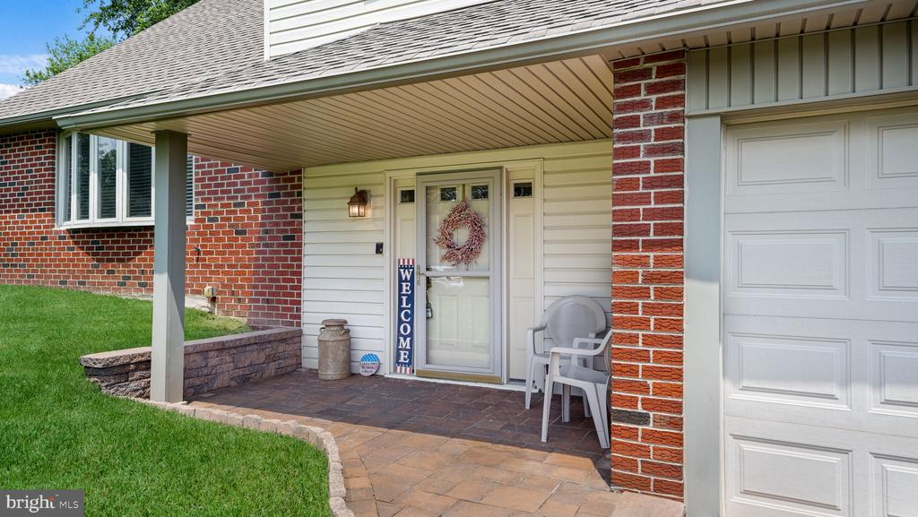 Home exterior with a covered brick entry, wreath-adorned front door, and paved walkway.