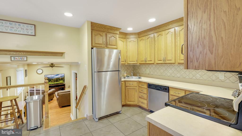 Kitchen with honey-colored cabinets, stainless-steel appliances, and an opening to the living area.