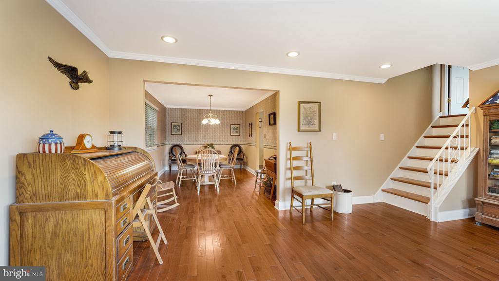 Dining room with hardwood floors, a wooden secretary desk, and an adjoining staircase.